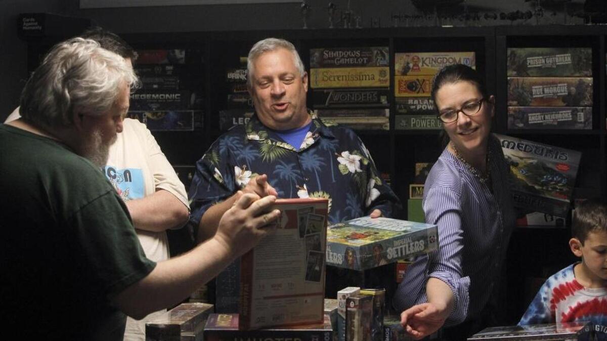 Chris Gryzwacz, center, Courtney Shinaberry and others sorted through new games last month at Jessie Dunn’s home in Lexington in preparation for the fourth annual LexiCon gaming convention.
