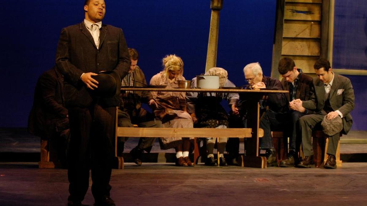 Jeremy Gillett as Jim Casey (standing) prays over the Joads: played by (L-R) Eric Russell Henninger, Conway Poteet, Casey Voris, Teresa Tope, Art Herman, Alex Koehl, Zach Moseley in the University of Kentucky and Bluegrass Community and Technical College’s 2009 production of The Grapes of Wrath.