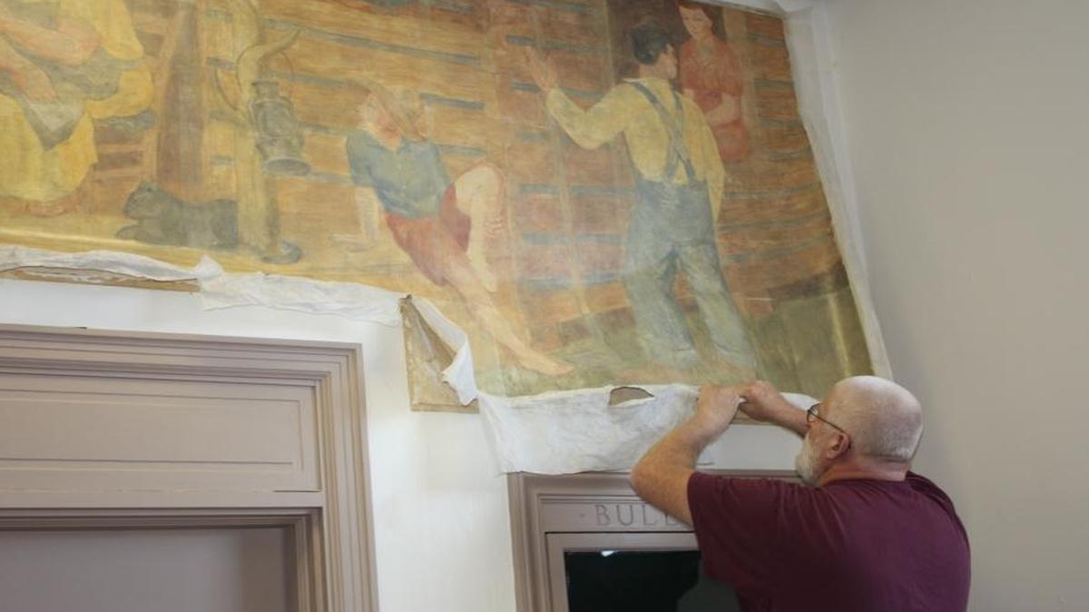 Steve Graves worked to remove Frank Long’s mural “Rural Free Delivery” from the wall of the Morehead police station.