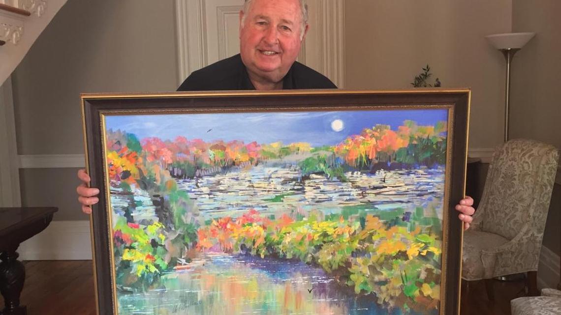 Neil Sulier holding his painting of the Kentucky River Palisades in the foyer of the office at the Dr. Thomas Hunt Morgan House.