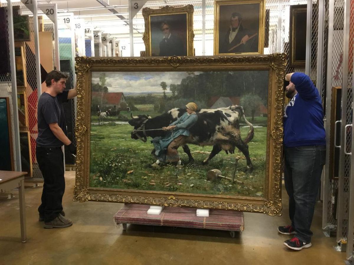 UK preparatorial assistant Nick Guagliardo and UK preparator Alan Rideout move Julien Dupré’s In the Pasture (1883) from the storage area at the University of Kentucky Art Museum, which owns the painting.
