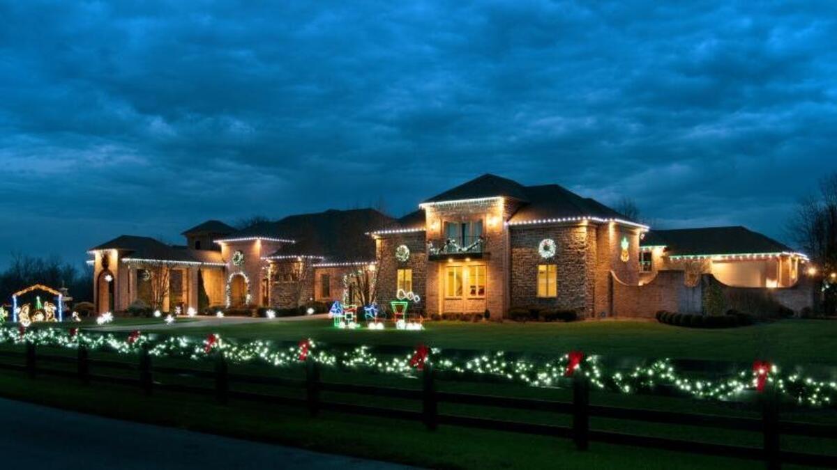 The exterior of the 11,000-square-foot home in rural Jessamine County is adorned with white lights, wreaths, garland, red bows and several large lighted displays.
