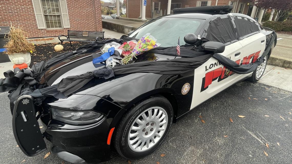The police cruiser of London police officer Logan Medlock, 26, who was killed Sunday in a fatal crash, is draped in black cloth, ribbon, and covered with flowers outside of the London Police Department.