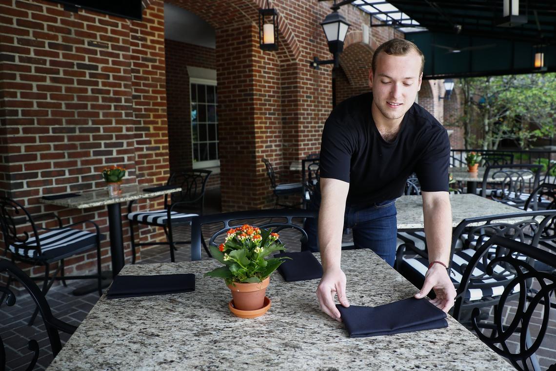 Server and bartender Jacob Tow, of Lexington, sets tables on the covered patio at the newly opened at Graze. The restaurant opens directly onto the patio overlooking a fountain.