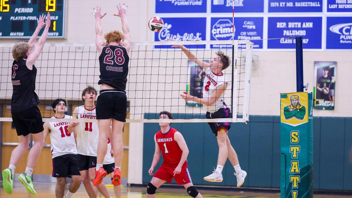 Lafayette’s Ben Marsh (2) spikes the ball through the defense of Tates Creek’s Cosmo Reynolds, left, and Zane Hinkle (28) during the 7th Region Boys Volleyball Tournament on Thursday at Bryan Station High School.