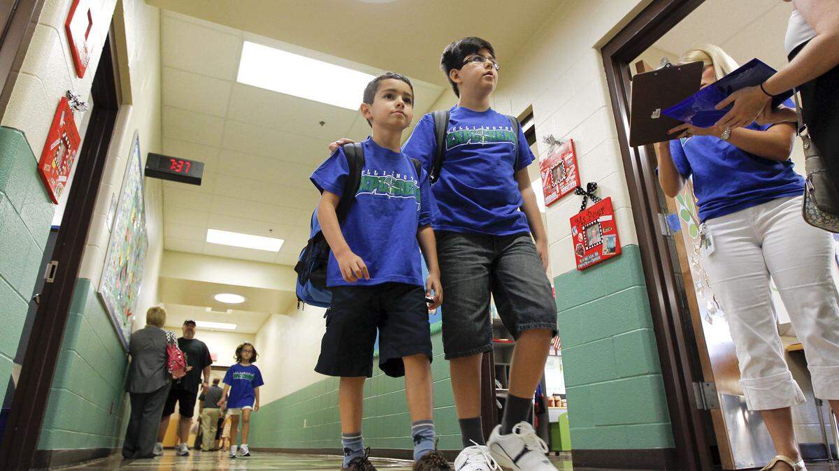 6-year old Milen Mikov, left, was guided to his first grade classroom by his brother, 9-year-old 4th grader Kali Mikov, right, on the first day of school for Fayette County students at Wellington Elementary on Keithshire Drive, in Lexington, Ky., Thursday, August 11, 2011. Wellington is a brand new school with many new environmentally friendly features. Between 525-550 students were expected on the first day. Charles Bertram | Staff