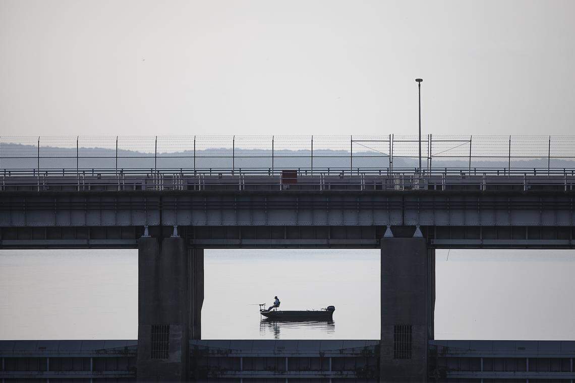 A fisherman in a boat is framed by Kentucky Dam on the county line between Livingston and Marshall counties in West Kentucky Monday, Aug. 5, 2019.