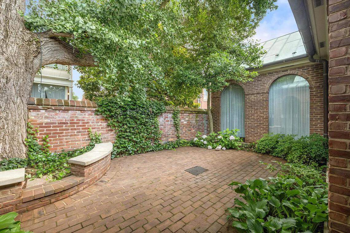 The courtyard at 220 Market Street in Lexington’s Gratz Park neighborhood. It's enclosed by a brick wall and lined with bricks. There's a seating area and beds for flowers and other shrubbery.