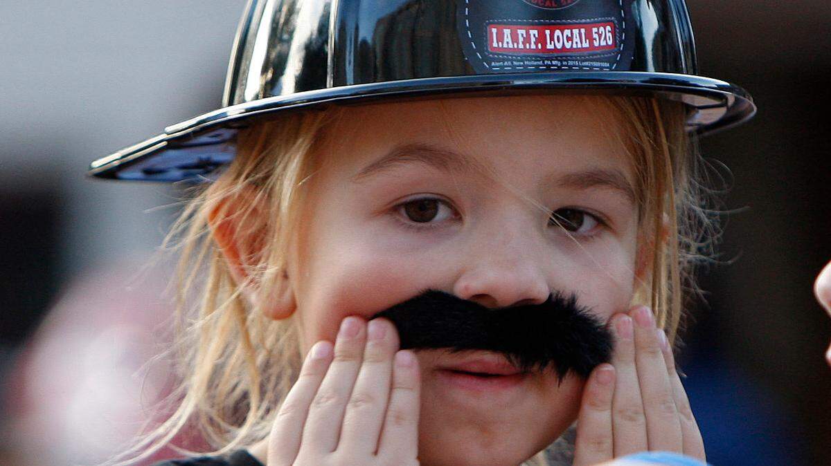 Junior fire chief Tegan Stanifer, whose father is a firefighter, adjusts her mustache at the Fire Prevention Festival at Courthouse Plaza in Lexington, Ky., Sunday, October 4, 2015. Photo by Matt Goins