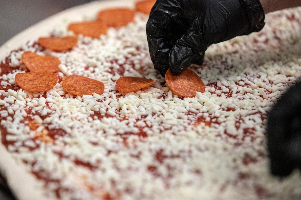 Curtis Gordon, places pepperoni on a Big Bambino at Big City Pizza in Lexington, Ky., on Thursday, Jan. 21, 2021. The price for Lexington's largest pizza? $34.99 per pizza, and $4.99 per topping.