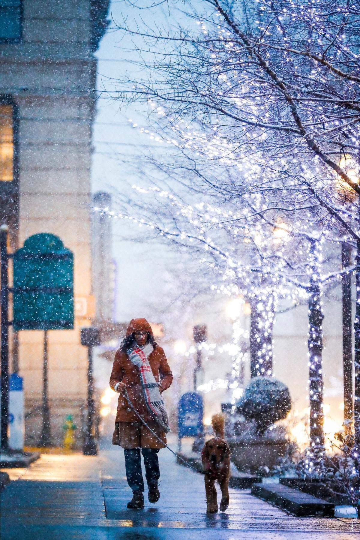 Kathy Artiles, of Lexington, Ky., walks with her golden retriever named Sasha along West Main Street as snow begins to fall in Lexington, Wednesday, Jan. 27. 2021. Several inches of snow is expected to blanket the city on Wednesday evening.