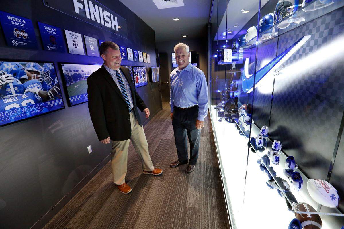 Freddie Maggard, Kentucky’s director of player development, left, shared a laugh with former UK fullback Andy Murray, right, while touring the locker room in UK’s practice facility. Reconnecting alumni, including successful businessmen like Murray, is part of Maggard’s job description.