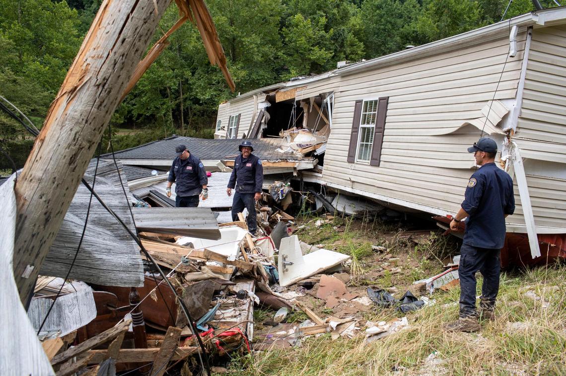 Members of the Lexington Fire Department look through the wreckage of a home while operating as search and rescue units along KY-476 along Troublesome Creek in Breathitt County, Ky., Sunday, July 31, 2022.