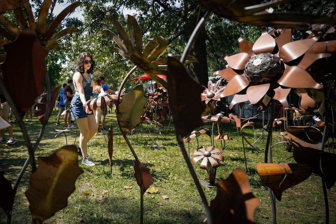 Amanda Judy, of Lexington, Ky., examines handmade metal garden sculptures at one of the dozens of booths at the Woodland Art Fair at Woodland Park in Lexington, Saturday, Aug. 21, 2021. The fair will continue on Sunday opening at 10 a.m.