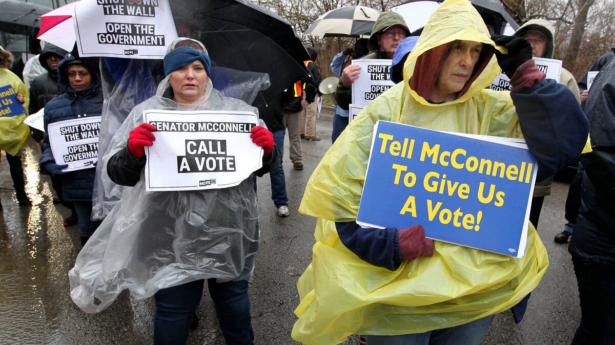 Federal employees, including Darcie Oubezza, left, and Mary O’Rourke, protested the partial government shutdown Wednesday outside Sen. Mitch McConnell’s Lexington office.