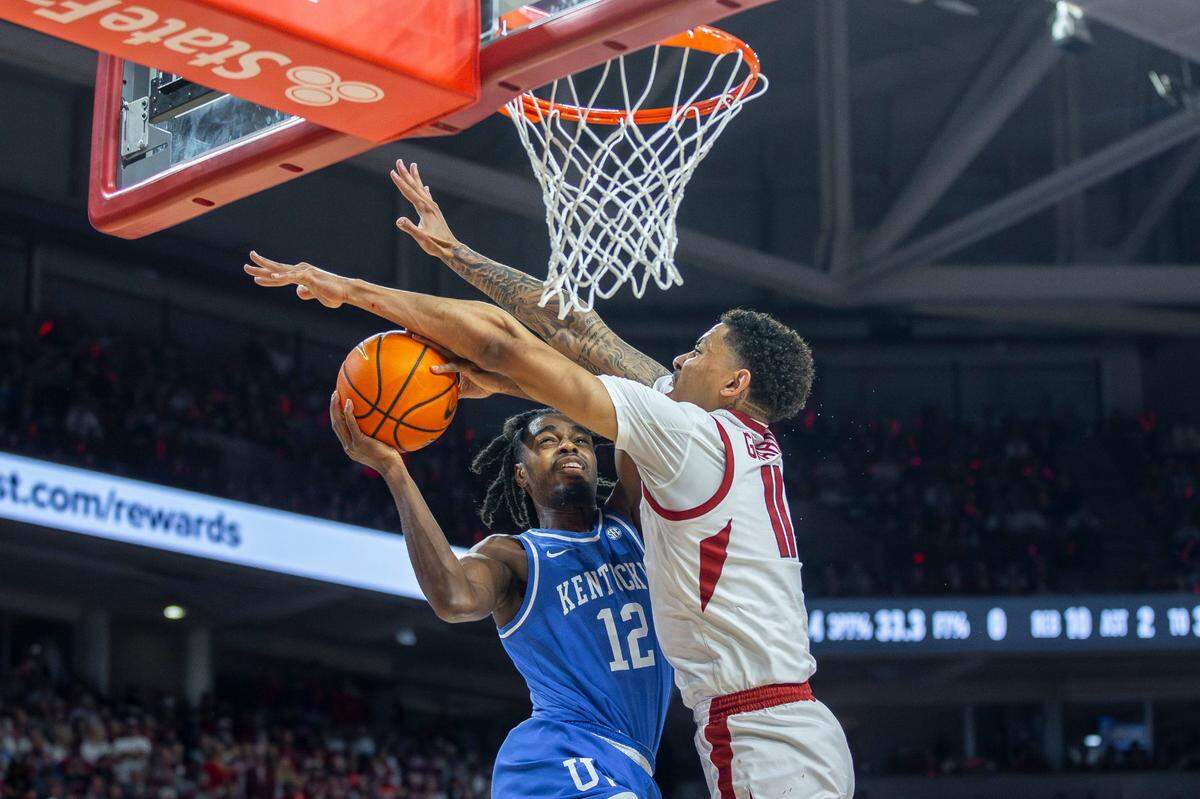 Kentucky’s Antonio Reeves (12) drives against Arkansas’ Jalen Graham (11) on Saturday night. Reeves led the Wildcats with 24 points on 9-for-20 shooting from the field and 4-for-8 from 3-point range.