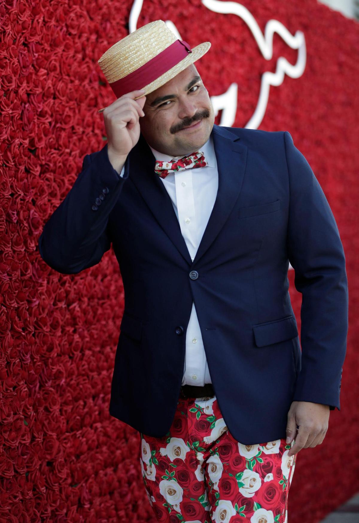 Christian Schirra tips his straw hat, that he paired with a rose print pant from Shinesty, that came with a complimentary bow tie, for the Kentucky Derby at Churchill Downs in Louisville, Ky., Saturday, May 1, 2021.