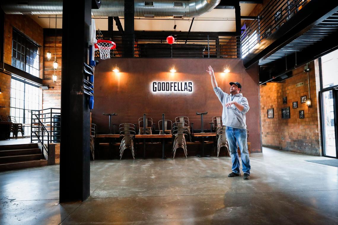 Goodfellas bartender Devin Paulding shoots baskets Saturday in the empty dining room in between lunch orders at Goodfellas in the Distillery District. Goodfellas plans to have their five existing locations open as long as they can.