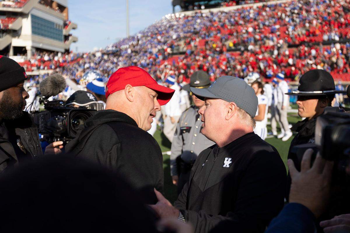 Kentucky coach Mark Stoops, right, shook hands with Louisville head man Jeff Brohm after the Wildcats upset the No. 9 Cardinals 38-31 in the 2023 regular-season finale at L&N Federal Credit Union Stadium.