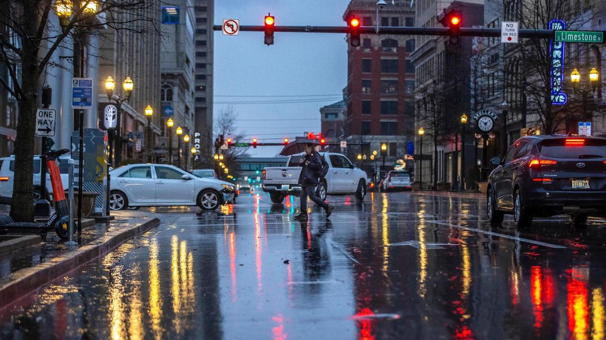 Will Carroll of Lexington crosses East Main Street during a rain storm in downtown Lexington, Ky., on Thursday, Jan. 12, 2023.