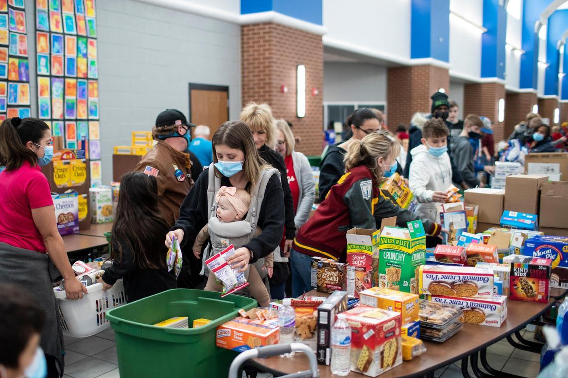 Volunteer Molly Westbook, carrying her baby Riley, helps sort and gather essential supplies from donations for people whose homes were destroyed or damaged by tornados at South Warren High School in Bowling Green, Ky., Sunday, December 12, 2021.