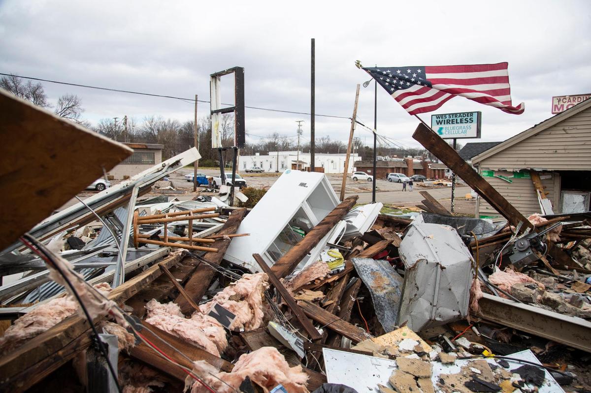 An American flag flies in the rubble of Total Image Audio Inc. on the 31W By-Pass road after a tornado came through the area in Bowling Green, Ky., Saturday, December 11, 2021.