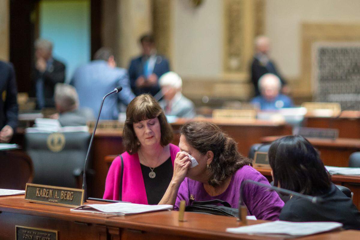 Kentucky Sen. Karen Berg, D-Louisville, is consoled by former state legislator Patti Minter, left, and Rep. Tina Bojanowski, D-Louisville, after SB 150 passed the Senate, 29-6, at the Kentucky state Capitol on Thursday, Feb. 16, 2023. The bill would allow teachers to choose whether or not to use a student’s pronouns. Berg’s transgender son died by suicide in December.