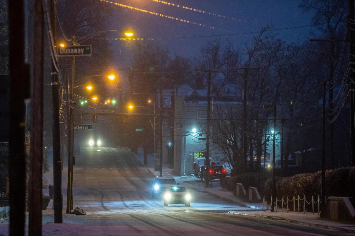 Vehicles drive along a snow-covered West Maxwell Street in Lexington, Ky., on Friday, Feb. 4, 2022.