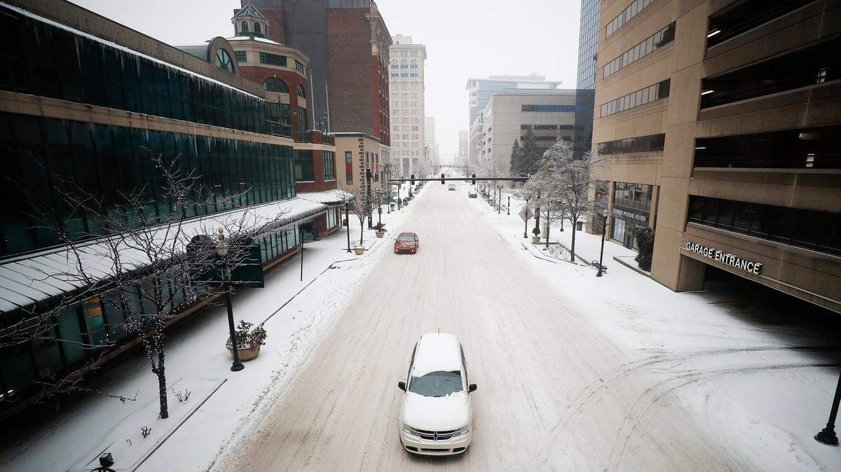A man crosses a snow covered West Main Street at Mill Street in downtown Lexington, Ky., Monday, Jan. 15, 2021.