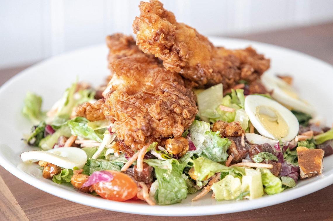 Bella Cafe & Grille’s crispy chicken salad, with cafe greens, heirloom tomatoes, hen’s egg, pancetta, smoked peanuts and honey mustard dressing.