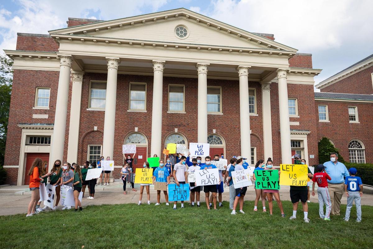 Players and parents held up signs during a rally in support of fall high school sports on Monday at the Fayette County Public Schools building in Lexington.