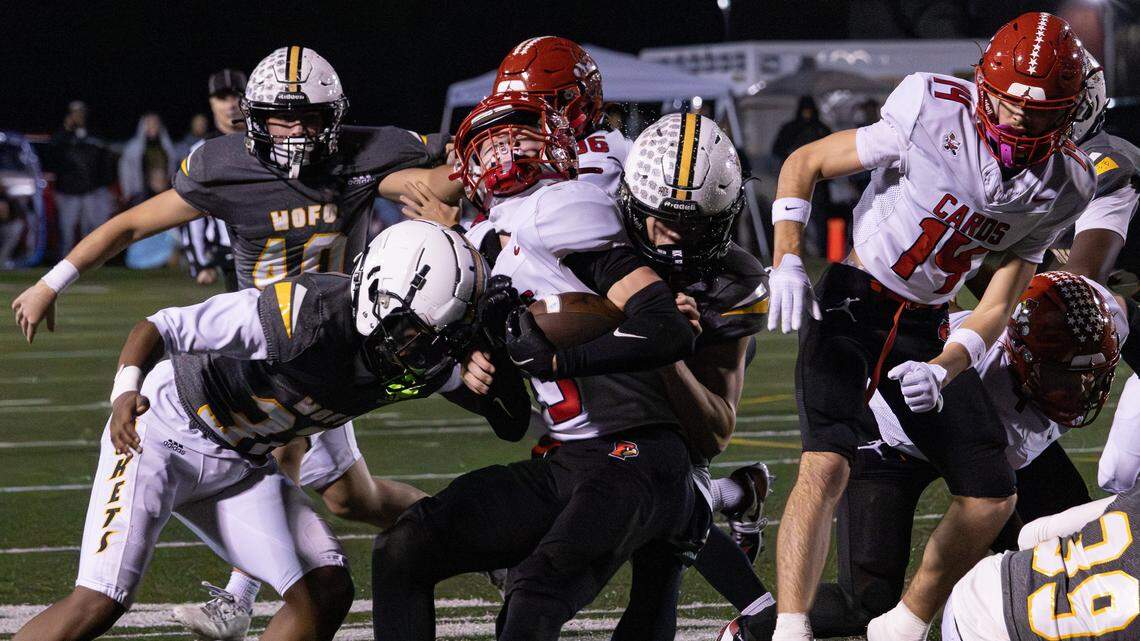 Yellow Jackets Alex Senters (33) and Cassius Hocker (37) stop Cardinals Asher Brewer (3) for a loss of yards during the Class 5A Region Championship game between Scott County and Woodford County on Nov. 21, 2025, at the Community Stadium at Falling Springs Center in Versailles, Ky.