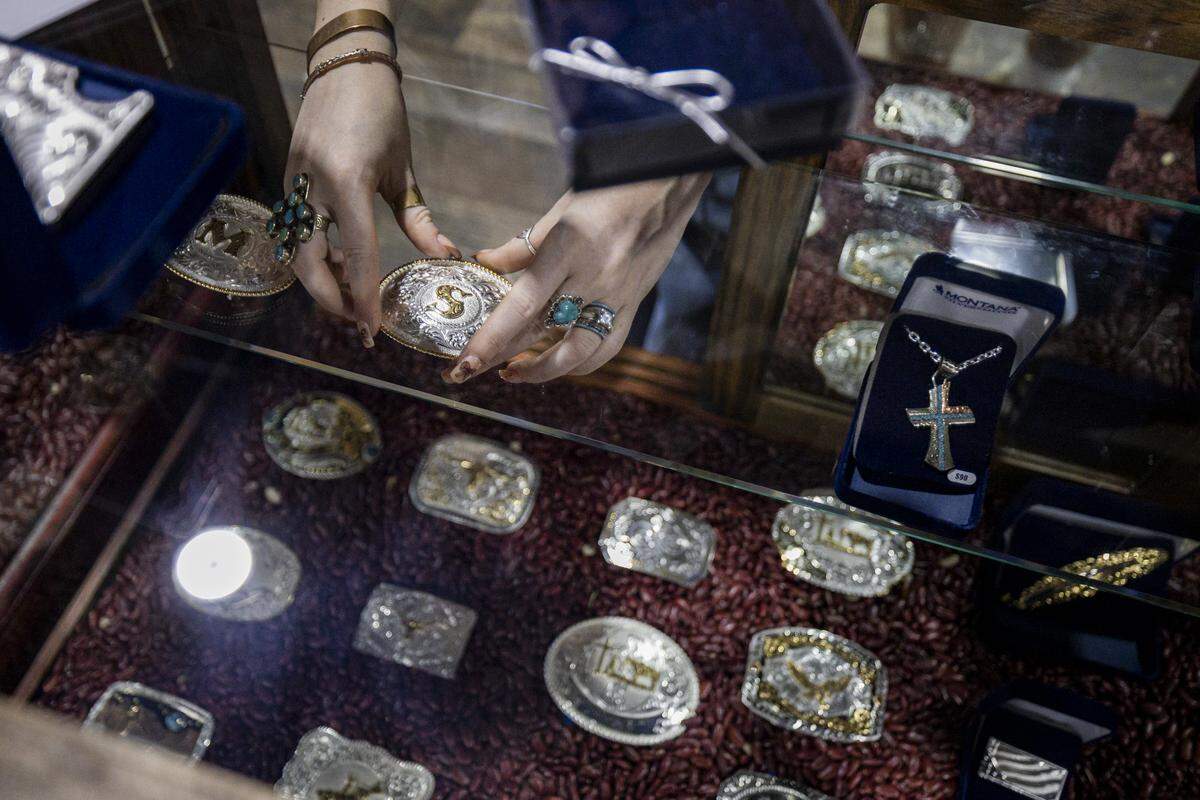 A worker places belt buckles in a display case at Cavender’s during a tour on Thursday, Aug. 21, 2025, at Fayette Mall in Lexington, Ky. 