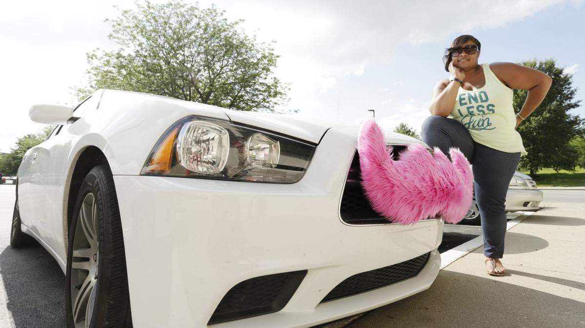 Lyft driver Michele Delbridge has her vehicle outfitted with the company's signature pink mustache on its front bumper.  