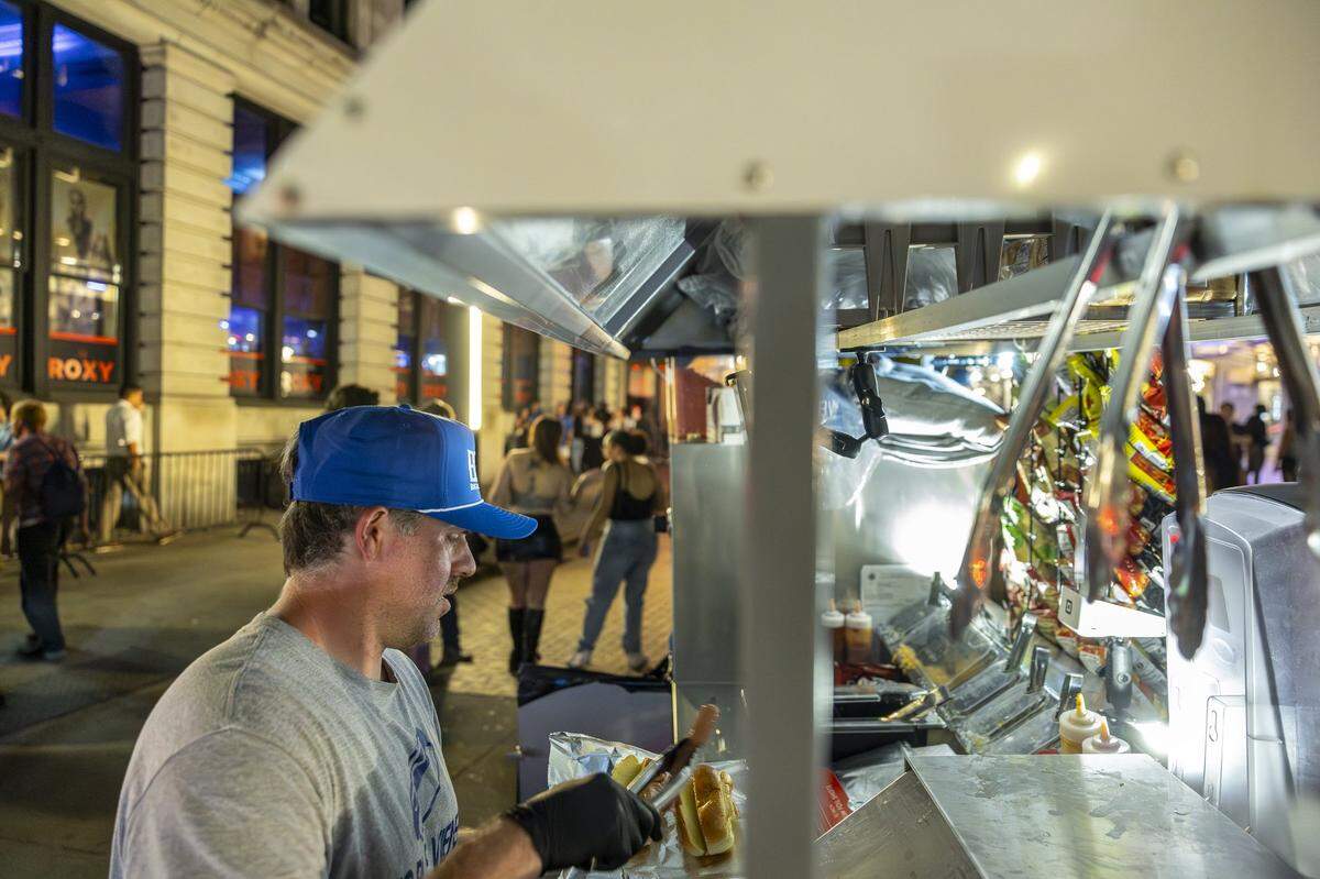 Chris Price, the owner and operator of Big Blue Wiener, prepares hot dogs for customers at his stand near Henry A. Tandy Centennial Park in downtown Lexington, Ky., in the early hours of Sunday, Sept. 14, 2025.