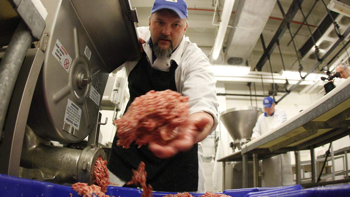 Gregg Rentfrow pulled out meat that had been mixed with spices and fruit mix for bourbon apple bratwurst at UK's meat lab. The lab, working with UK food services, makes sausage and other meat products to sell and to serve on campus.  