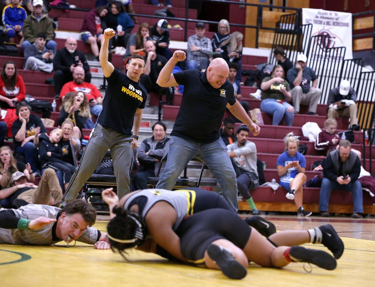 Woodford County head wrestling coach Travis Baney, left, and girls’ wrestling coach Brent Courtney reacted as Tanyea Ramirez, wearing gray uniform, defeated Bullitt East’s Mariah Gardner .