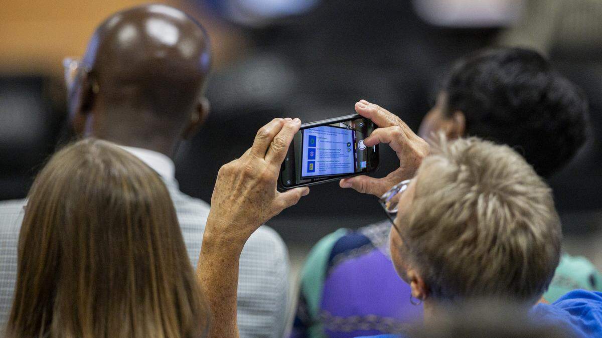 An attendee takes a photo of a proposed action to help the budget deficit during a school board meeting on Monday, Aug. 18, 2025, at Fayette County Public Schools Central Office in Lexington, Ky. 