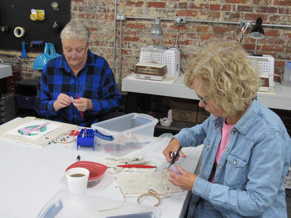 Teressa Phipps, left, and Carla Hatfield worked on a stained-glass cross Phipps was creating Dec. 12, 2019, at Willing Hearts in Cumberland. The center is a ministry where students learn to create pieces that raise money for retired and disadvantaged people.