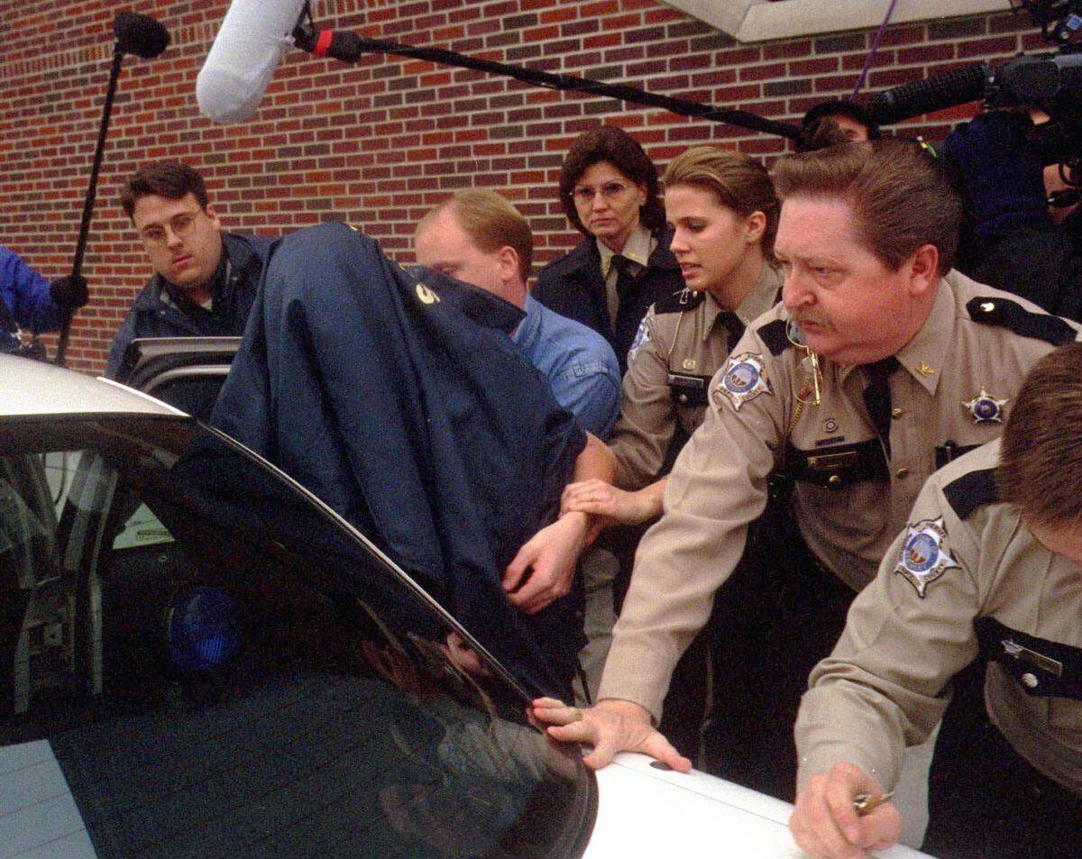 McCracken County, Ky. Sheriff’s deputies and juvenile officers hustle Michael Carneal (covered by jacket), the 14-year-old accused killer of three Heath High School students, into a car for transport to a holding facility on Wednesday, Dec. 10, 1997. (AP Photo/The Paducah Sun, Barkley Thieleman)