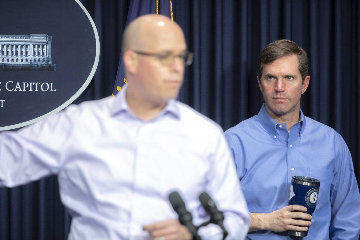 Kentucky Gov. Andy Beshear looks on as Dr. Steven Stack, Kentucky public health commissioner, speaks about the novel coronavirus during a media conference at the state Capitol in Frankfort, Ky., on Sunday, April 5, 2020.