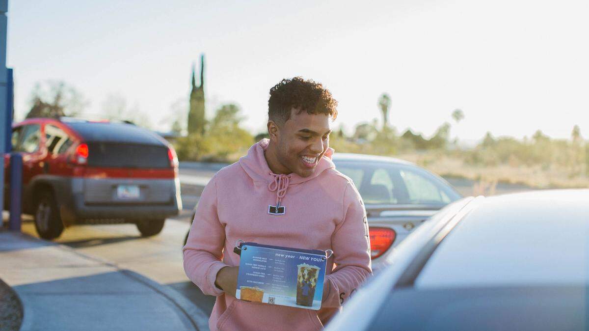 A “broista” takes an order at a Dutch Bros Coffee drive-thru, where passionate fans line up for coffee.