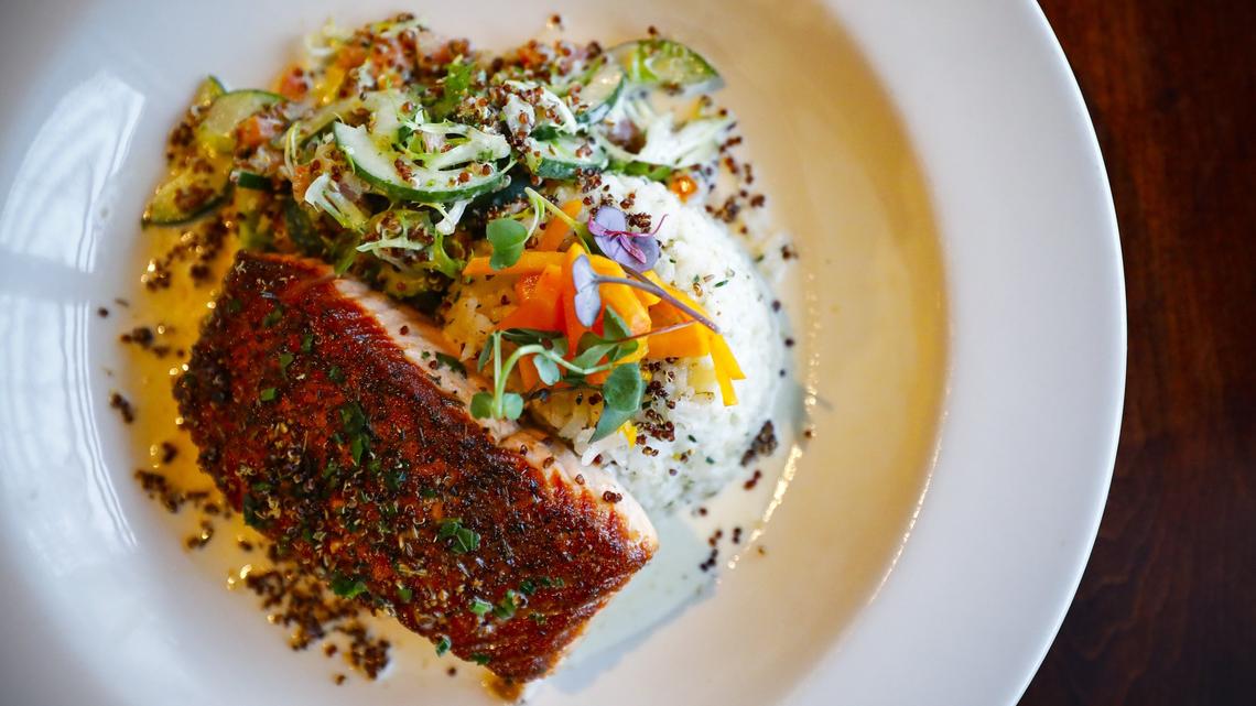 Pan seared salmon with white grits and a chilled quinoa cucumber salad garnished with pickled radish and rosemary at The Tulip Bar & Bistro in Lexington.