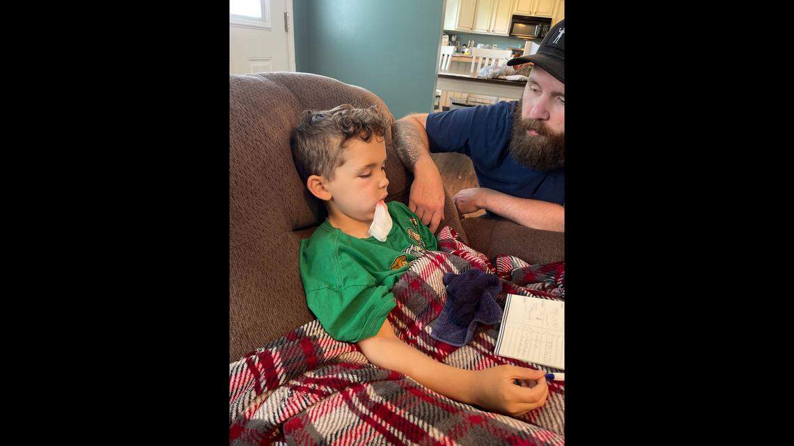Jonah Reynolds sits with his father in May 2022 after a doctor extracted a tooth that caused him severe pain.