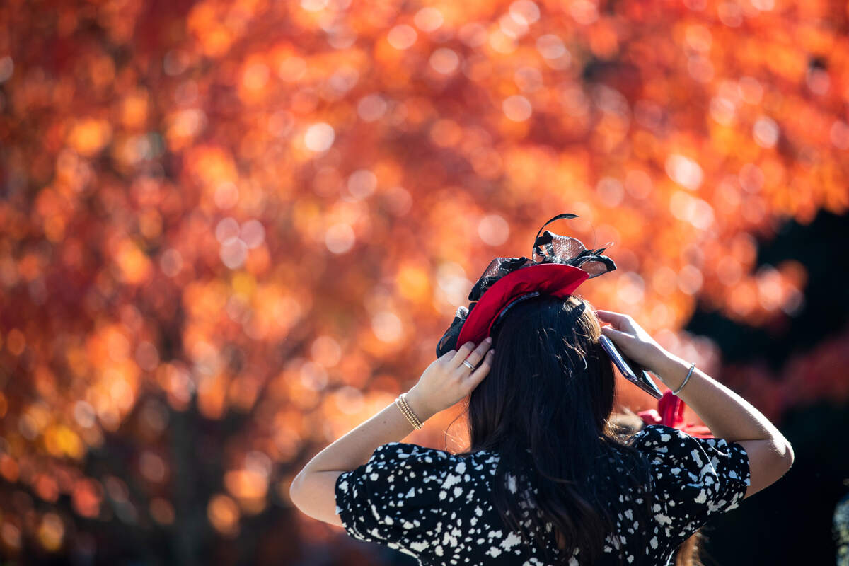 A woman adjusts her hat while walking through the paddock during the first day of the Breeder’s Cup World Championships at Keeneland in Lexington, Ky., Friday, November 6, 2020.