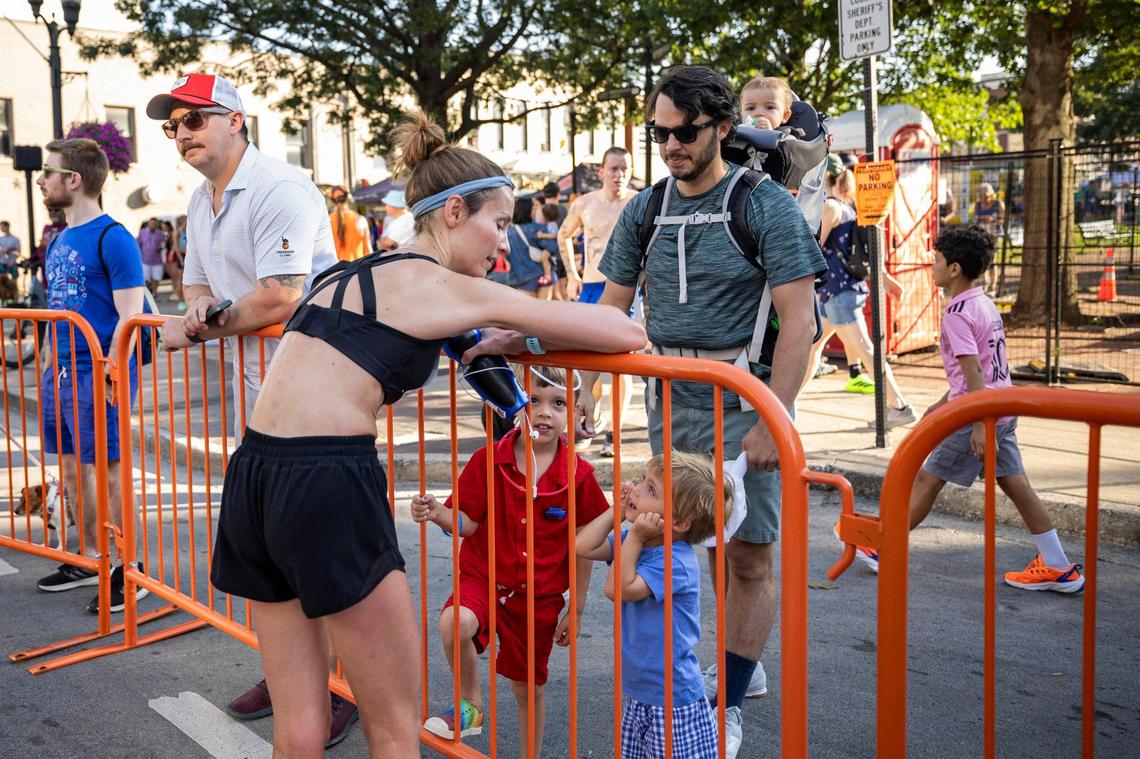 Eva Burgess, talks with Caius, left center, and Constantin, right center, while her husband, Logan Burgess, right, holds their daughter, Aurelia during the Bluegrass 10K road race.
