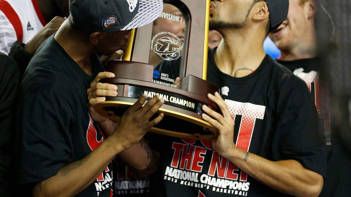 Louisville guards Russ Smith and Peyton Siva kiss the championship trophy after the Cardinals defeated Michigan on Monday night. Photo by Mark Cornelison | Staff