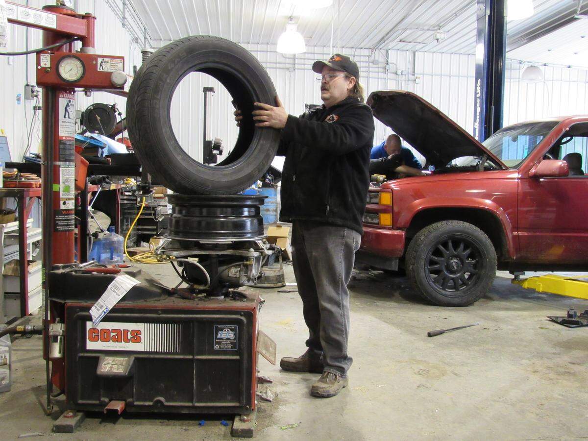 Lonnie Thomason works to repair a tire at Second Chance Auto in Louisa, Ky. The shop trains people to be mechanics while they are in treatment for addiction.