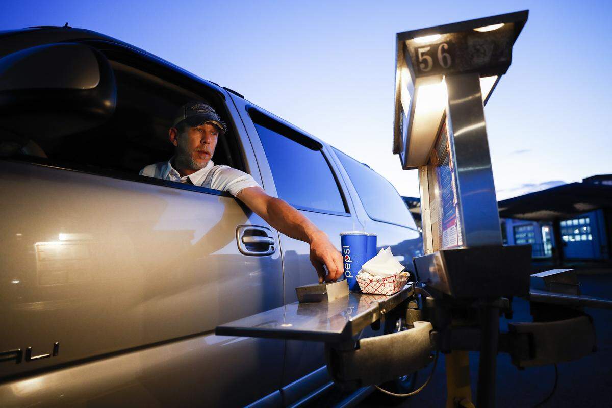 Jamie Spivey orders a Spare Tire Burger May 2 at a carhop intercom at the Parkette Drive-In restaurant. The retro restaurant opened in 1951 with no indoor seating.