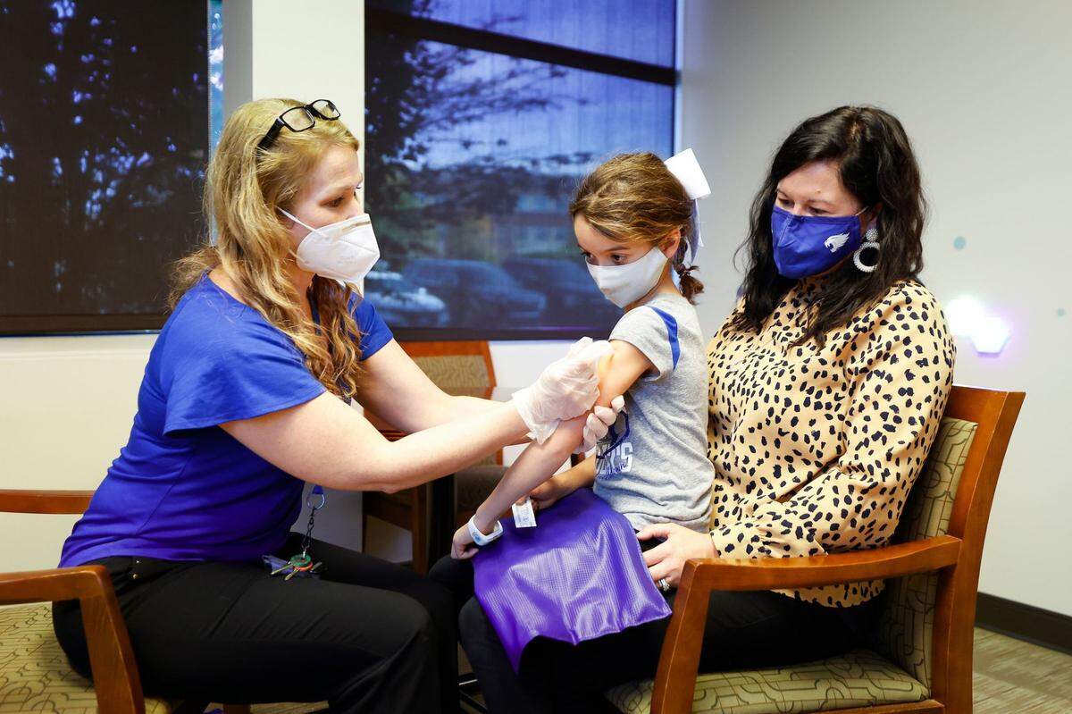 Sophia Dezarn, 8, sits with her mother Morgan Dezarn as she receives the Pfizer COVID-19 vaccine from Lindsay Ragsdale, M.D., interim medical director of Kentucky Children’s Hospital.